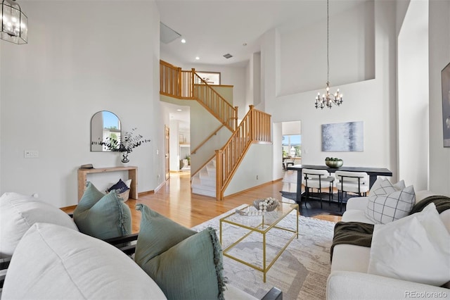 living area with a chandelier, stairs, a towering ceiling, wood finished floors, and baseboards