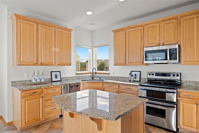 kitchen with appliances with stainless steel finishes, a sink, light brown cabinetry, light stone countertops, and light tile patterned flooring