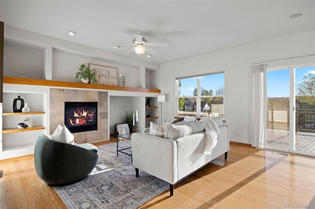 living area featuring built in shelves, healthy amount of natural light, and wood finished floors