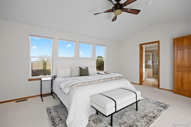 bedroom featuring vaulted ceiling, light colored carpet, baseboards, ensuite bath, and a ceiling fan
