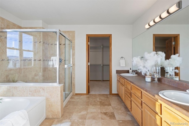 full bath featuring a shower stall, double vanity, a garden tub, and a walk in closet