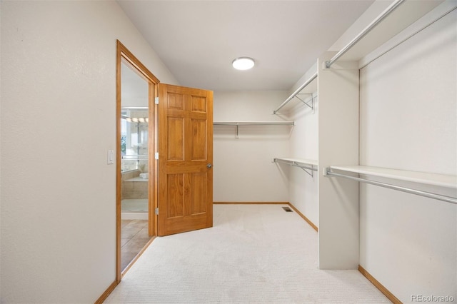 walk in closet featuring light colored carpet