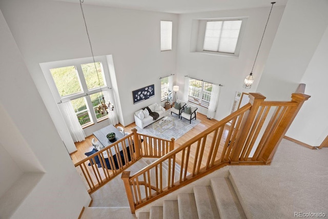 staircase with a towering ceiling, carpet floors, and baseboards