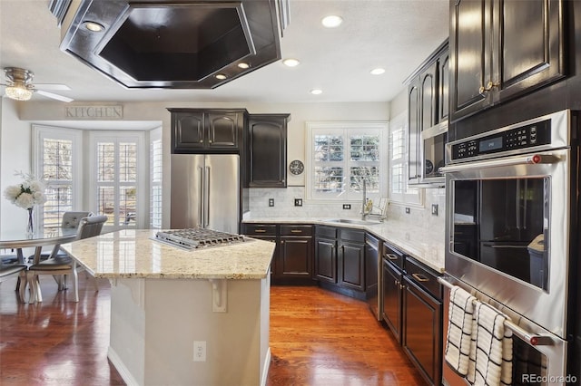 kitchen featuring sink, a center island, stainless steel appliances, wall chimney exhaust hood, and dark wood-type flooring