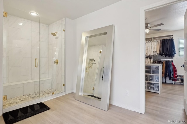 bathroom featuring ceiling fan, wood-type flooring, and walk in shower