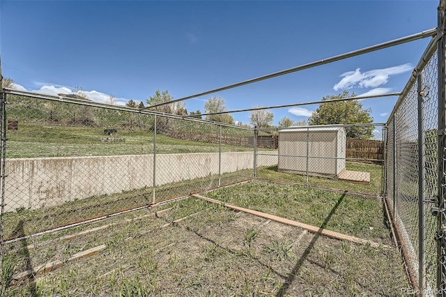 view of yard featuring an outdoor structure, a fenced backyard, a vegetable garden, and a storage unit