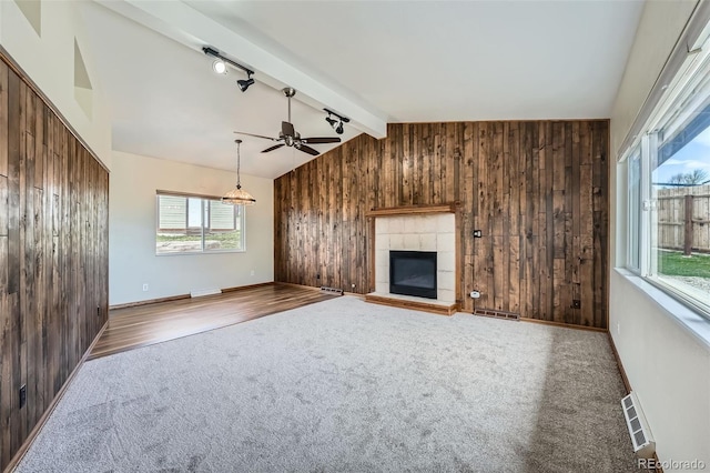 13805 W 82nd Ave, Arvada, CO 80005 - unfurnished living room with ceiling fan, rail lighting, lofted ceiling with beams, wooden walls, and carpet flooring