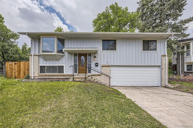 1477 S Wright St, Lakewood, CO 80228 - bi-level home with an attached garage, board and batten siding, concrete driveway, and brick siding