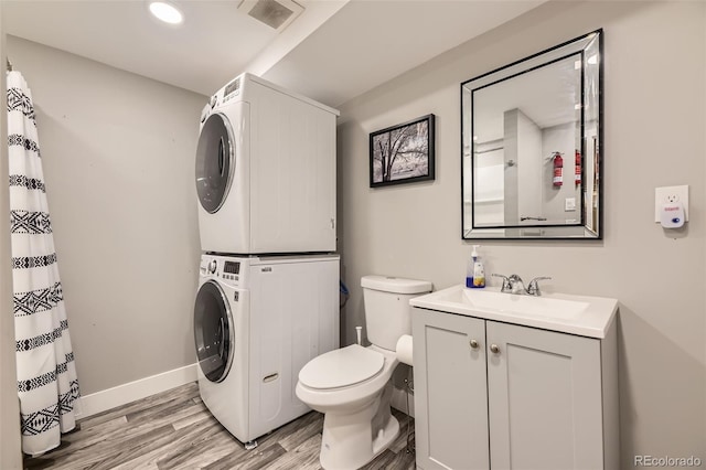 1477 S Wright St, Lakewood, CO 80228 - full bath featuring stacked washer / dryer, wood finished floors, toilet, vanity, and baseboards