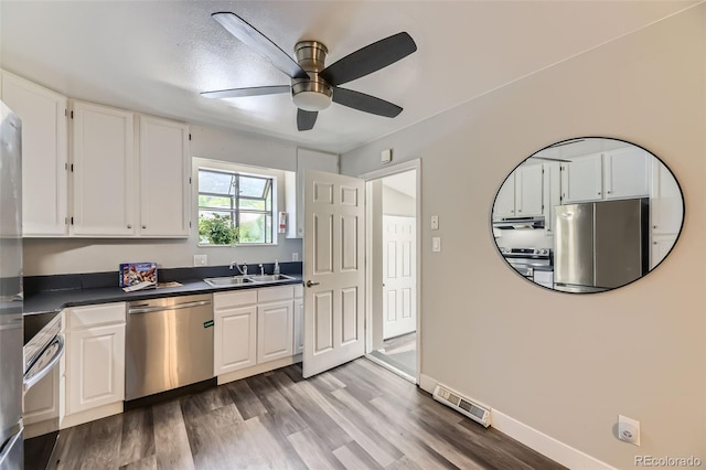 1477 S Wright St, Lakewood, CO 80228 - kitchen with stainless steel appliances, dark countertops, a sink, white cabinets, and light wood-type flooring
