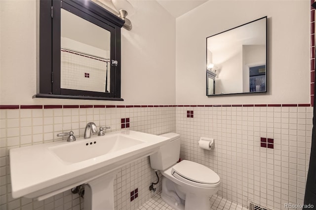 1477 S Wright St, Lakewood, CO 80228 - bathroom with tile walls, toilet, a wainscoted wall, tile patterned floors, and a sink