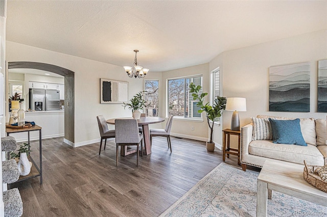 dining room with baseboards, arched walkways, a chandelier, and dark wood-type flooring