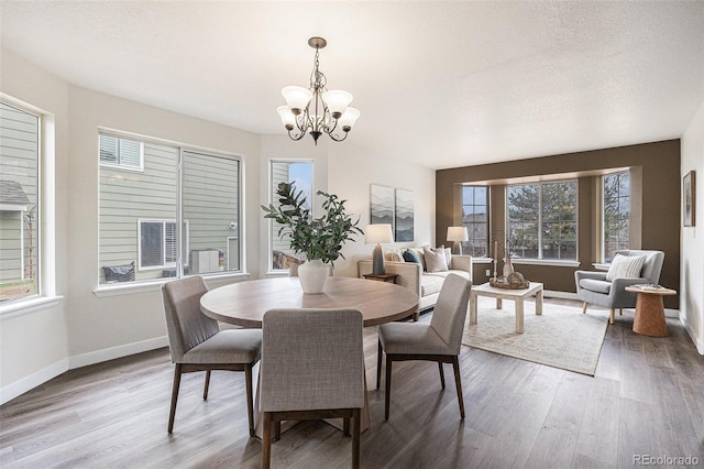 dining room featuring a textured ceiling, baseboards, a chandelier, and wood finished floors