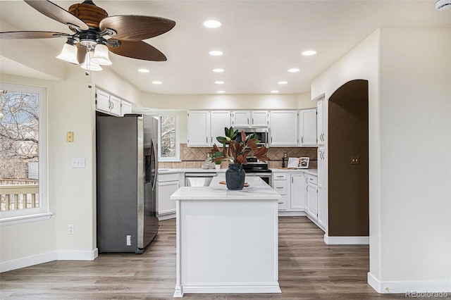 kitchen featuring wood finished floors, light countertops, appliances with stainless steel finishes, and backsplash