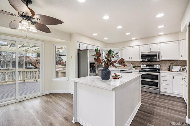 kitchen with plenty of natural light, appliances with stainless steel finishes, decorative backsplash, and dark wood-type flooring