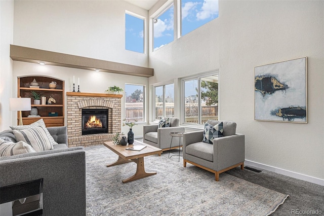 living area featuring built in features, carpet, a fireplace, visible vents, and baseboards