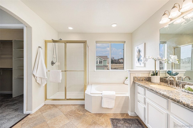 full bathroom with a stall shower, baseboards, a bath, and vanity