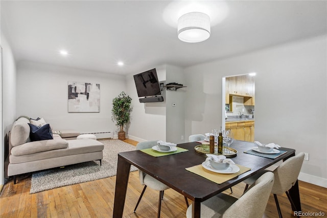 dining space featuring a baseboard heating unit and light hardwood / wood-style flooring