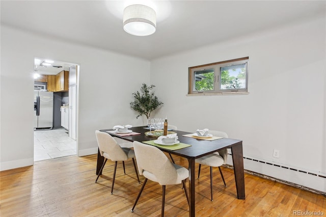 dining space with light hardwood / wood-style floors and a baseboard heating unit