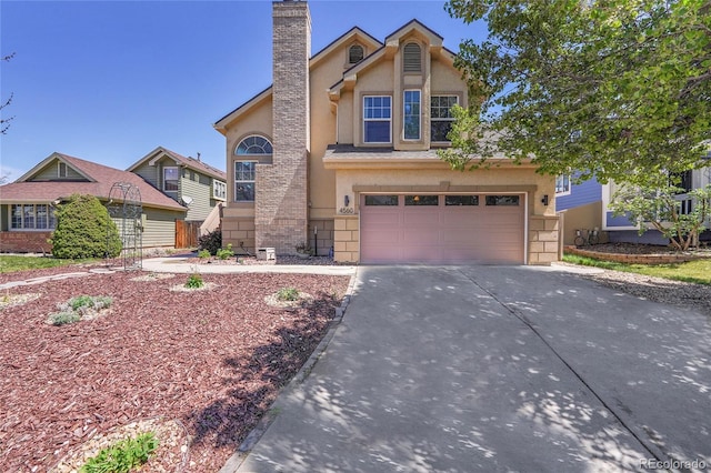 view of front of house with driveway, stucco siding, a garage, and a chimney