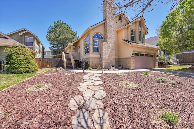 view of front of house featuring a garage, a chimney, fence, driveway, and stucco siding