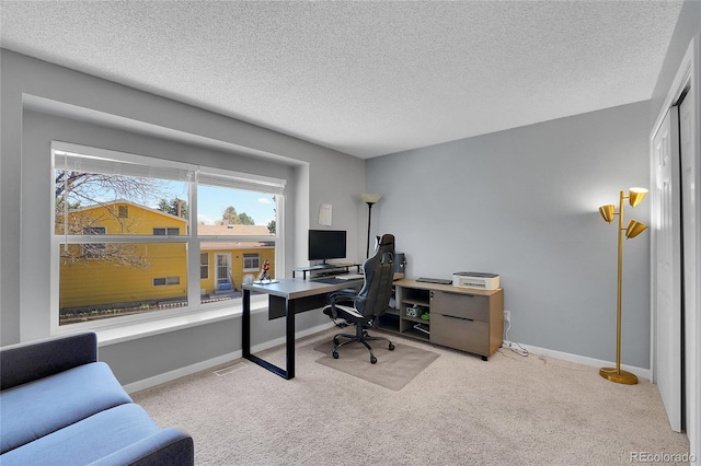 office featuring a textured ceiling, light carpet, and baseboards