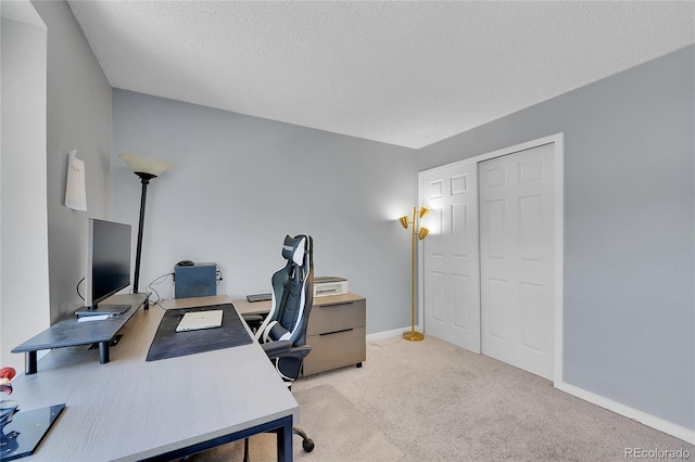 office space with light carpet, a textured ceiling, and baseboards