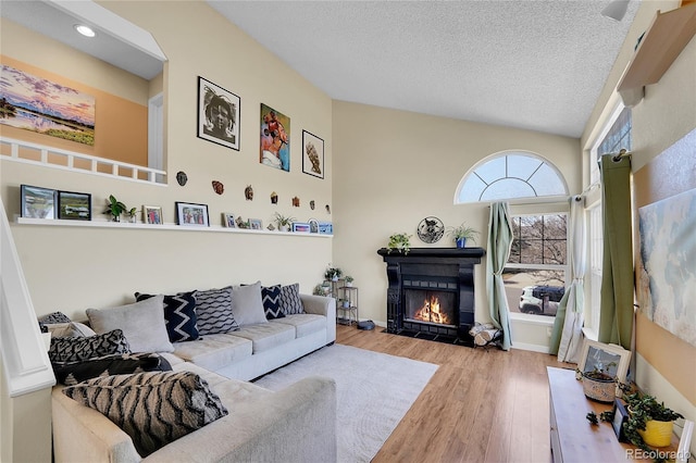 living area with a fireplace with flush hearth, wood finished floors, a textured ceiling, and recessed lighting