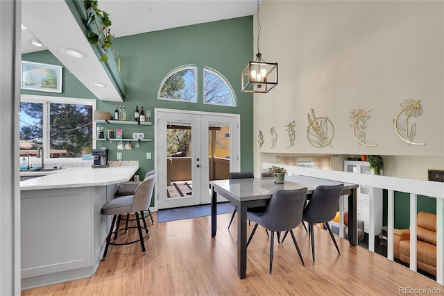 dining area with french doors, a chandelier, light wood finished floors, recessed lighting, and high vaulted ceiling