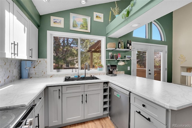 kitchen featuring dishwasher, lofted ceiling, a sink, open shelves, and tasteful backsplash