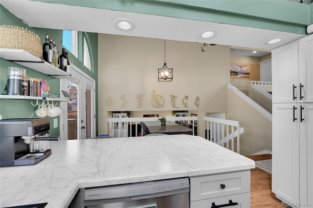 kitchen featuring dishwasher, white cabinets, hanging light fixtures, a peninsula, and light wood-type flooring