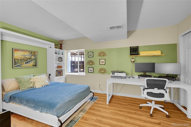 bedroom featuring wood finished floors, an office area, and baseboards