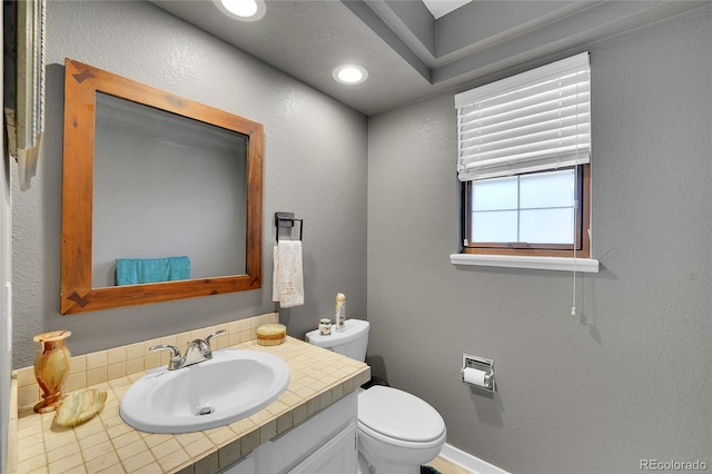 bathroom with toilet, vanity, and baseboards