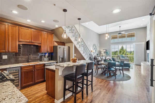 248 Writers Way, Colorado Springs, CO 80903 - kitchen with stainless steel refrigerator with ice dispenser, wine cooler, light wood finished floors, open floor plan, and brown cabinets