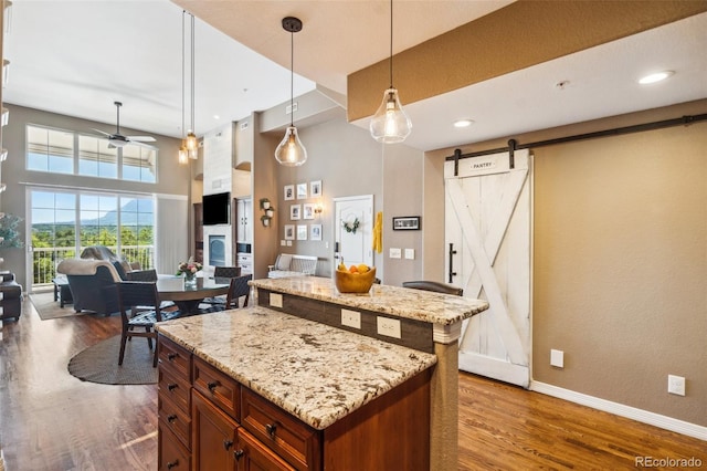 248 Writers Way, Colorado Springs, CO 80903 - kitchen featuring a barn door, a center island, open floor plan, dark wood-type flooring, and a towering ceiling