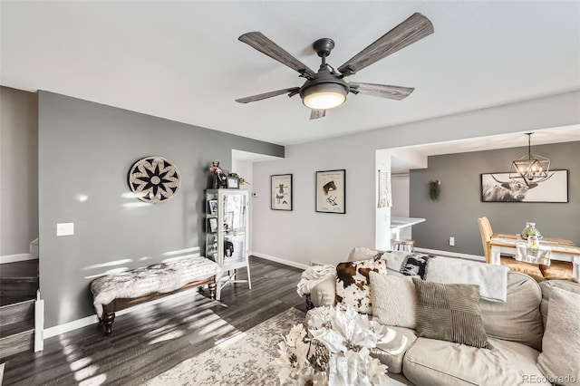 living room featuring ceiling fan with notable chandelier and dark wood-type flooring