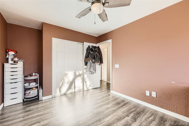 unfurnished bedroom featuring ceiling fan, a closet, and hardwood / wood-style flooring