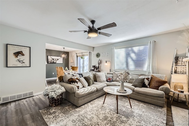 living room featuring ceiling fan with notable chandelier and dark wood-type flooring