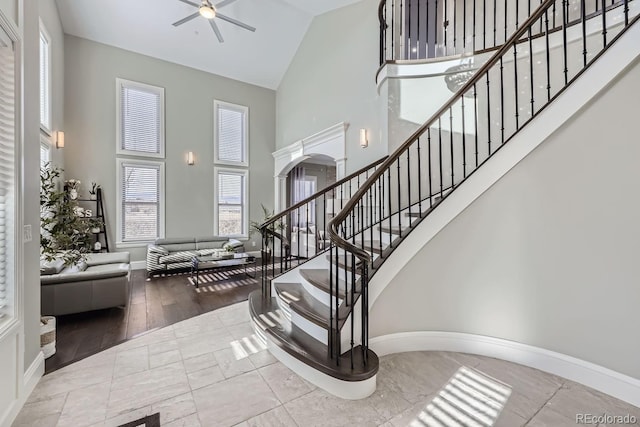 staircase featuring ceiling fan, a high ceiling, and hardwood / wood-style floors