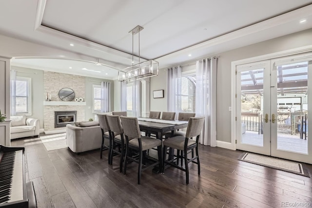 dining area featuring a fireplace, a raised ceiling, plenty of natural light, and dark hardwood / wood-style flooring