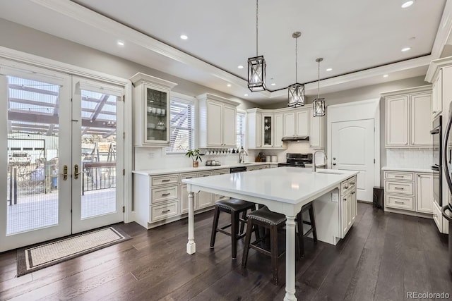 kitchen with a kitchen bar, sink, stainless steel electric range oven, a tray ceiling, and a center island with sink