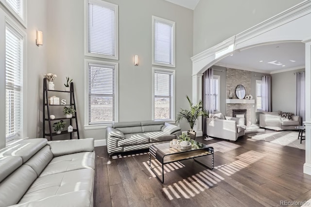 7587 Wright Ct, Arvada, CO 80005 - living area featuring arched walkways, a fireplace, hardwood / wood-style floors, a high ceiling, and ornamental molding