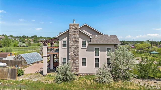 7587 Wright Ct, Arvada, CO 80005 - back of property featuring an exterior structure, stucco siding, an outbuilding, a chimney, and roof with shingles