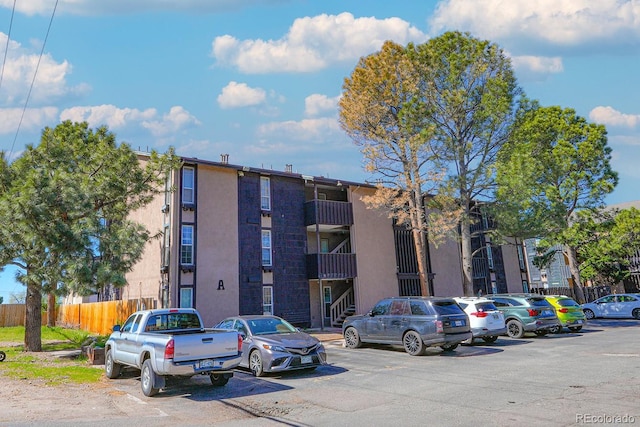 view of property with uncovered parking and fence