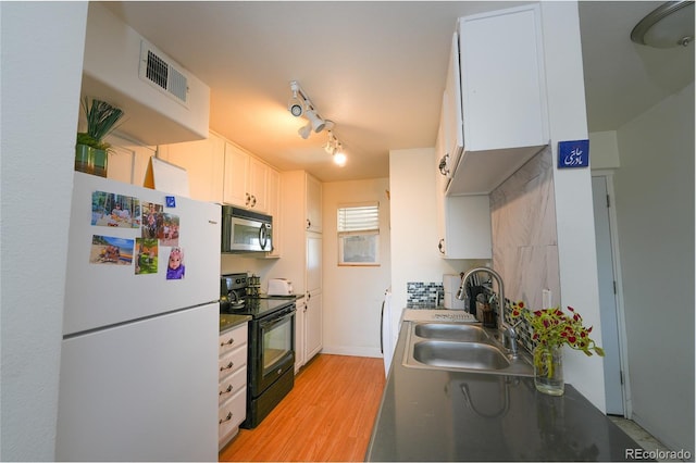 kitchen with freestanding refrigerator, black electric range oven, visible vents, a sink, and stainless steel microwave