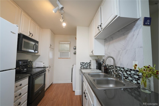 kitchen featuring freestanding refrigerator, a sink, stainless steel microwave, black range with electric stovetop, and backsplash