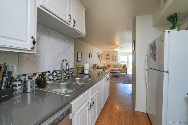 kitchen with freestanding refrigerator, light wood finished floors, a sink, white cabinetry, and tasteful backsplash