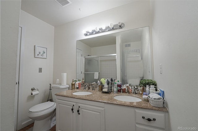 bathroom with toilet, visible vents, a sink, a shower stall, and double vanity