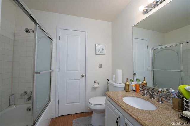 bathroom with vanity, toilet, bath / shower combo with glass door, and wood finished floors