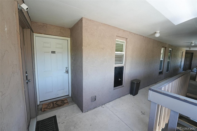 view of exterior entry featuring stucco siding and visible vents